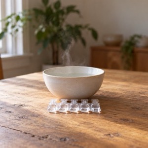 A strip of clear saline vials on a wooden table in front of a steaming bowl